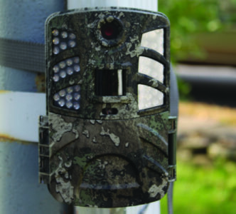 outdoor trail camera with an aged facade posted outside a building